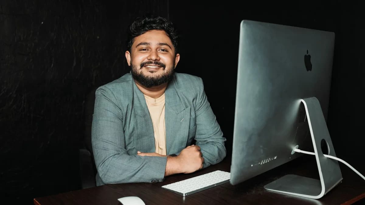 Confident businessman sitting at desk, working on computer in modern office.