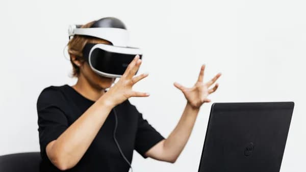 Adult using VR headset and laptop for a virtual reality experience indoors.