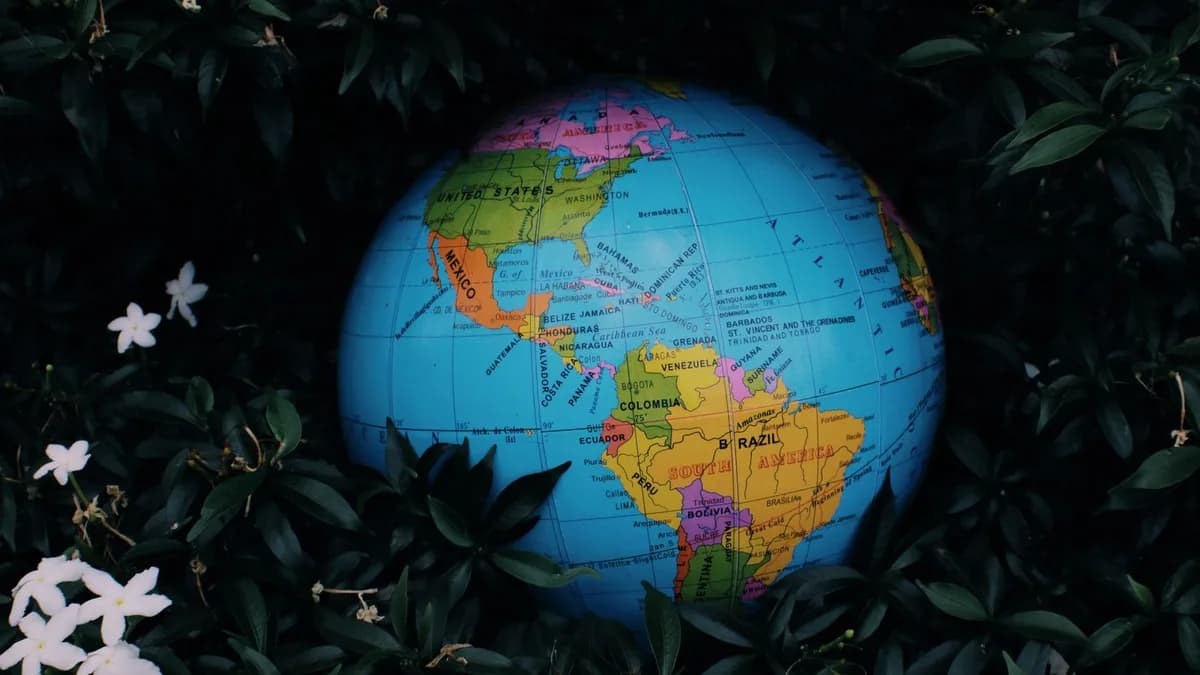 Earth globe toy placed in green bush with white flowers in nature in daytime