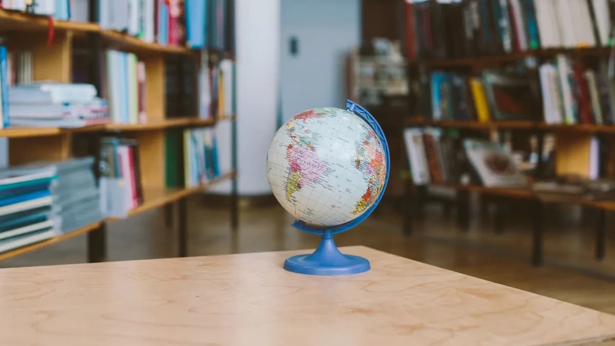 A globe in a quiet library setting, surrounded by shelves filled with books, represents education and exploration.