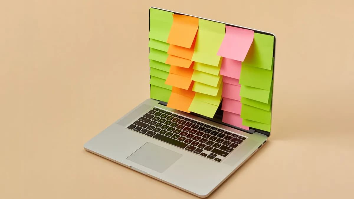 A sleek laptop with a screen covered in colorful sticky notes, depicting organization and task management.
