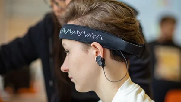 Close-up of a young woman wearing an EEG headband, showcasing modern technology indoors.