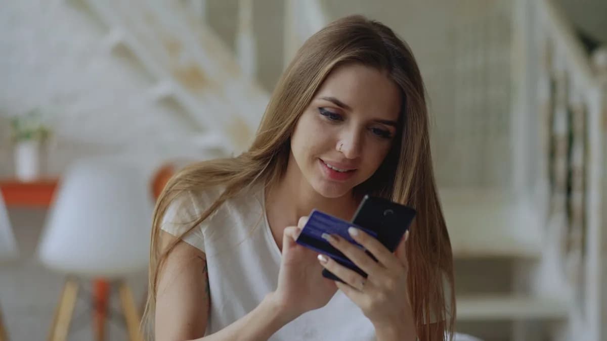 Woman using smartphone for online shopping with her credit card at home.