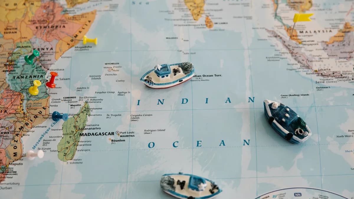 Detailed world map featuring toy ships and colored pins plotted over the Indian Ocean.